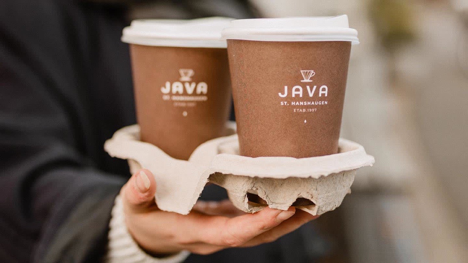 Kaffekopp med Java St. Hanshaugen-design, holdt i hånden